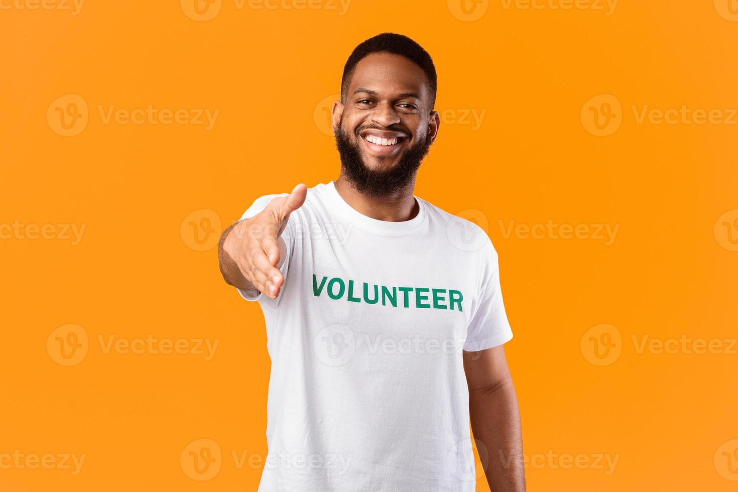 Cheerful Volunteer Guy Stretching Hand For Handshake Greeting To Camera Standing Posing In Studio Over Yellow Background. Voluntary Work, Join Our Volunteering Team Concept photo