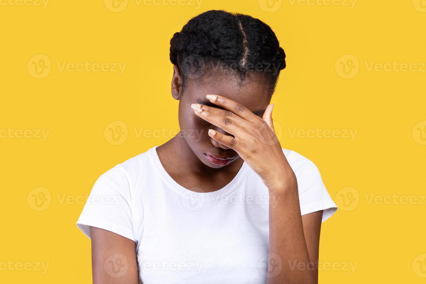 Female Depression. Depressed African American Woman Covering Face With Hand Having Problems And Suffering From Unhappiness Standing Over Yellow Studio Background. Sadness And Frustration Concept photo