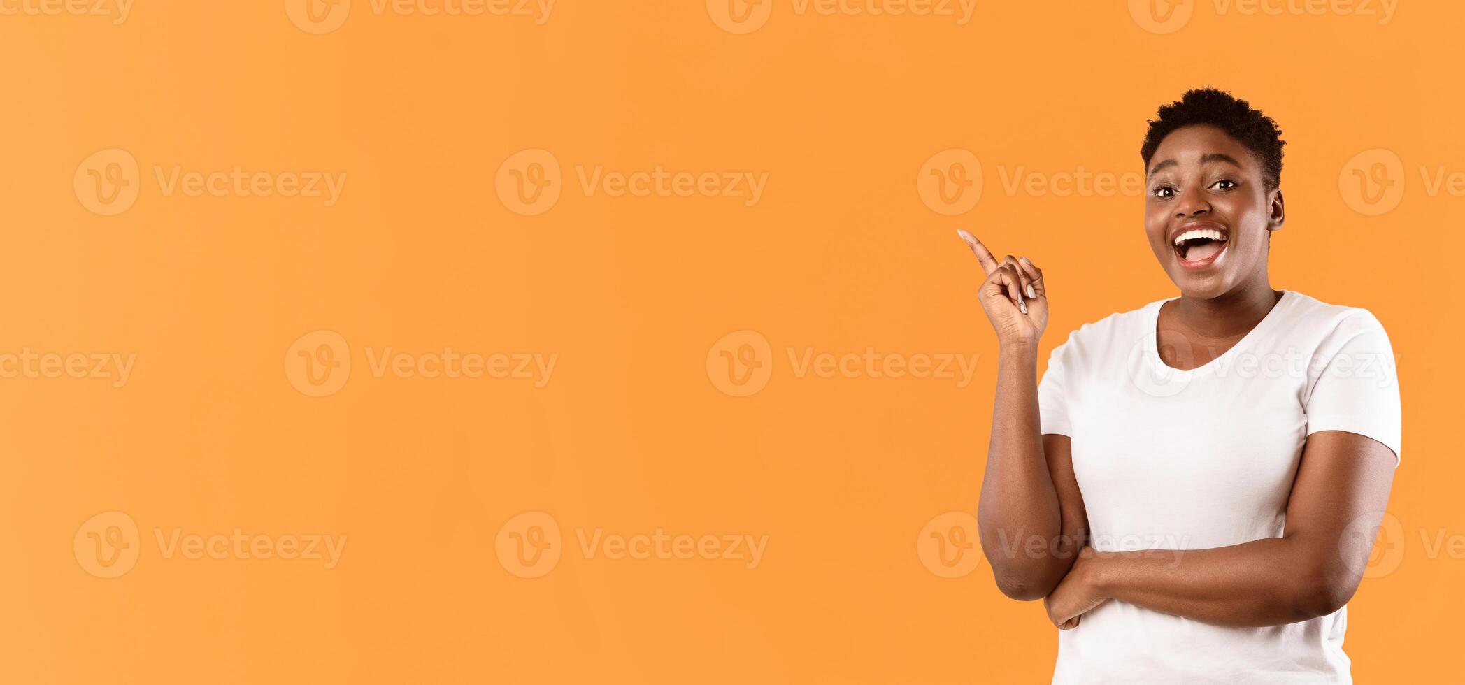 Cheerful Oversized African Woman Pointing Finger Up Having Idea Posing Standing Over Yellow Studio Background, Smiling To Camera. Inspiration, Eureka Moment. Free Space photo