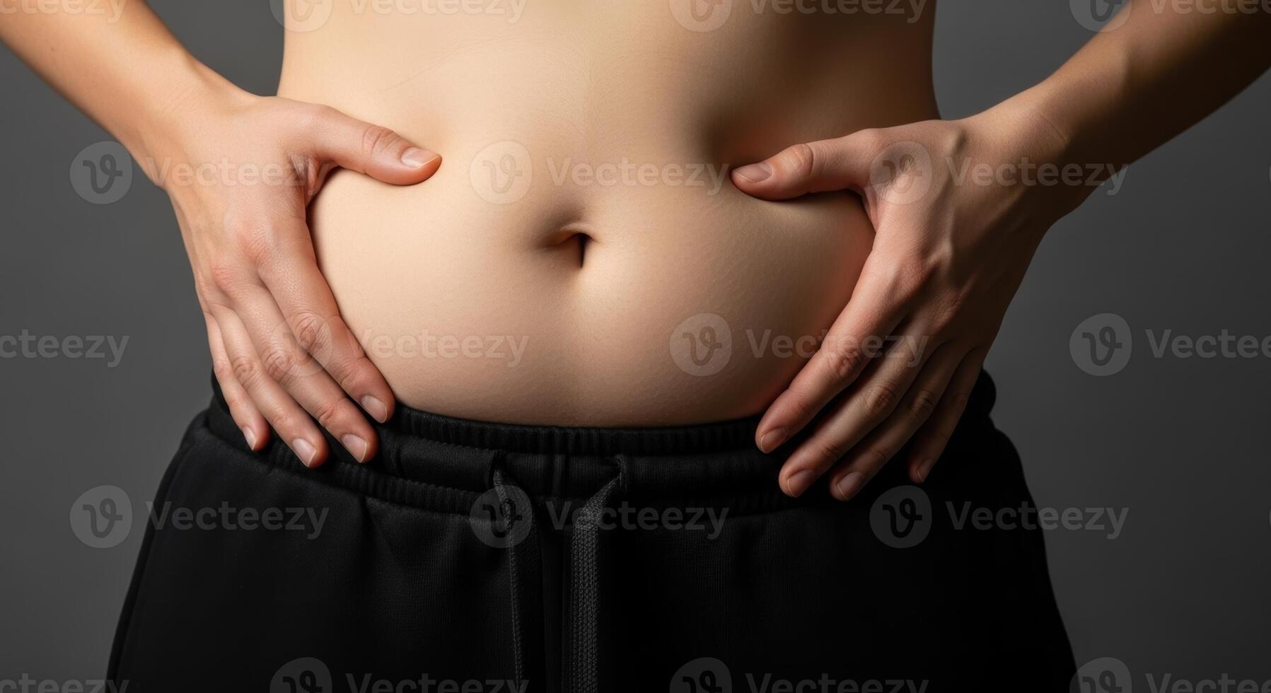 Close up of a woman midsection with hands holding and pinching excess belly fat. photo