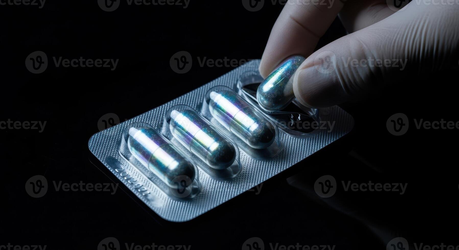 Close up of a gloved hand taking an iridescent capsule from a blister pack photo