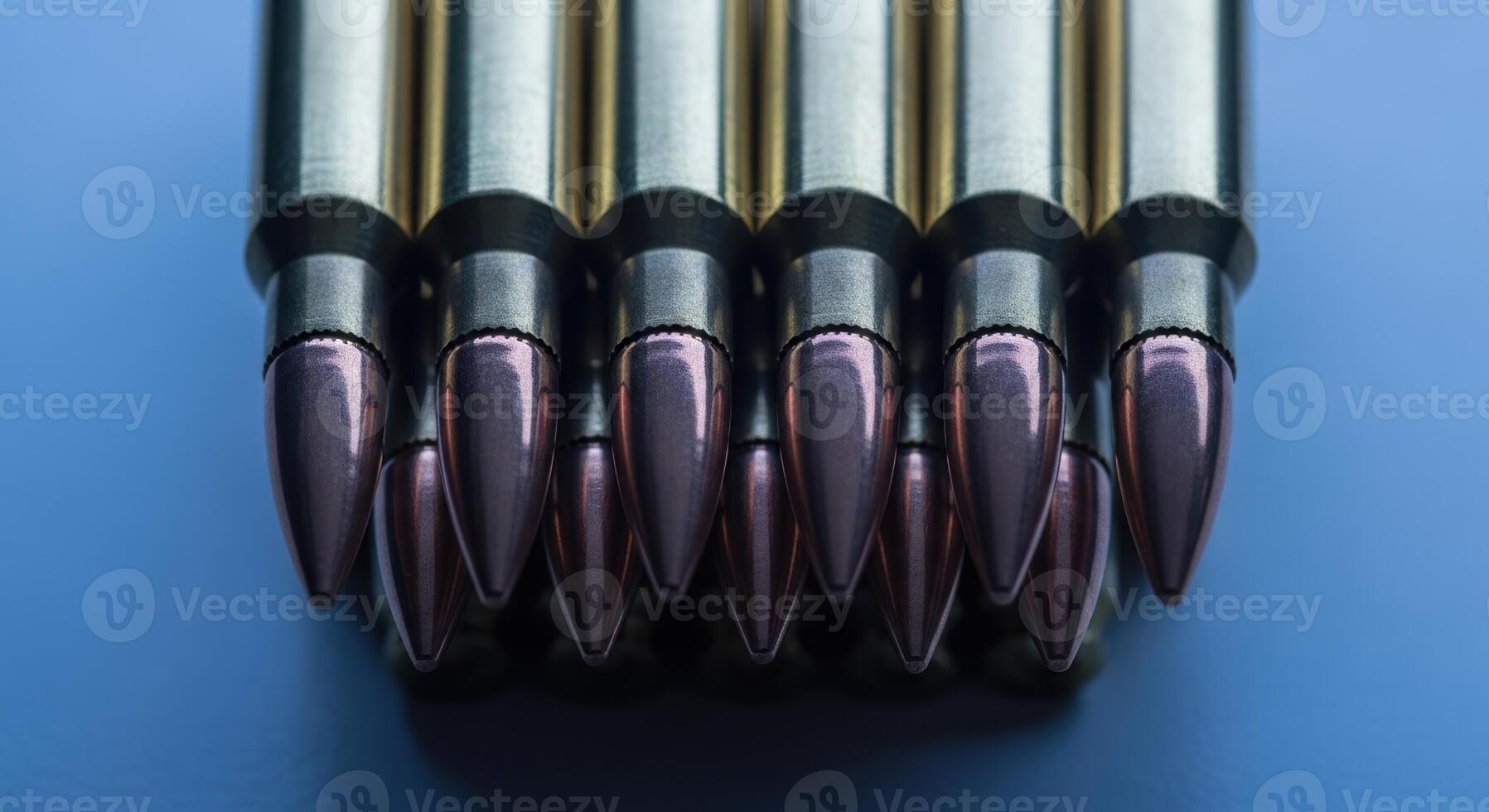 Close up view of shiny rifle ammunition cartridges neatly arranged on a blue surface photo