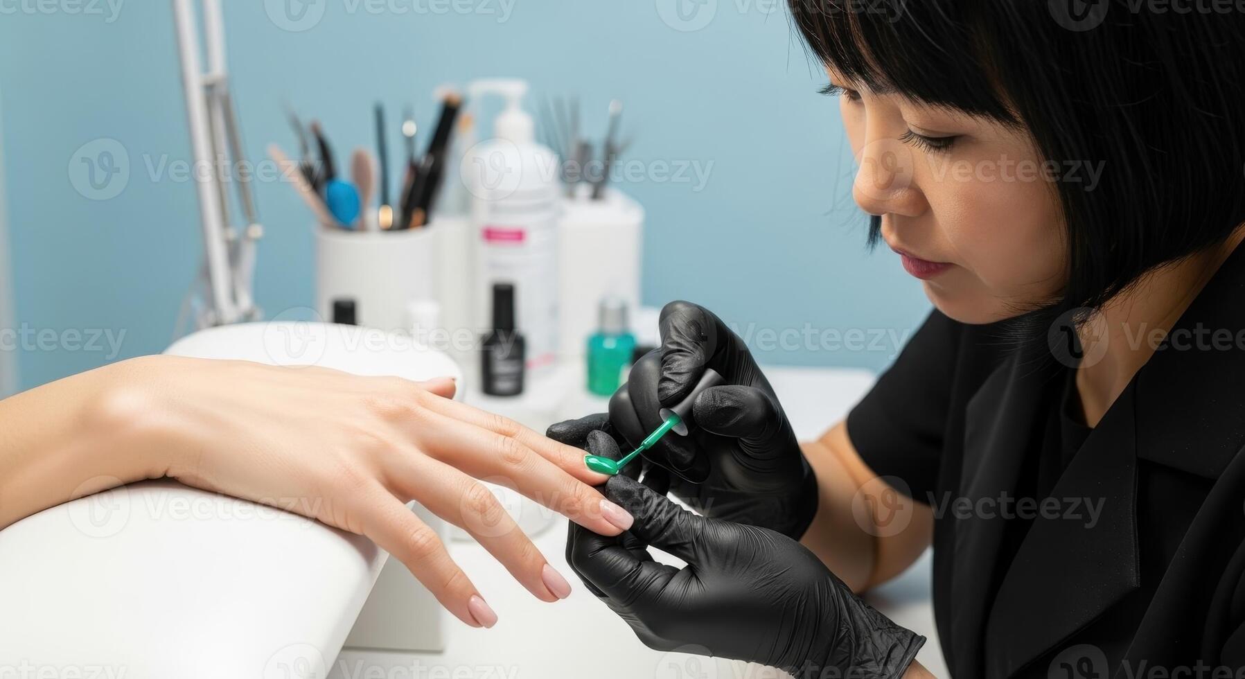 A manicurist applies green nail polish to a woman fingernails in a beauty salon. photo