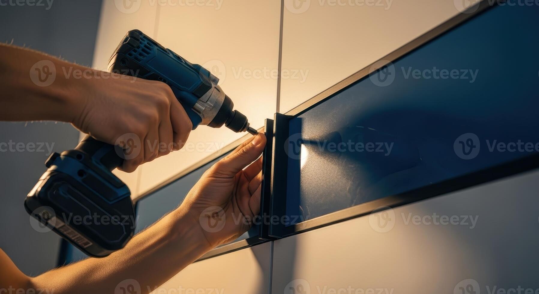 Man hands using a cordless drill to install a bracket on a blue wall panel photo