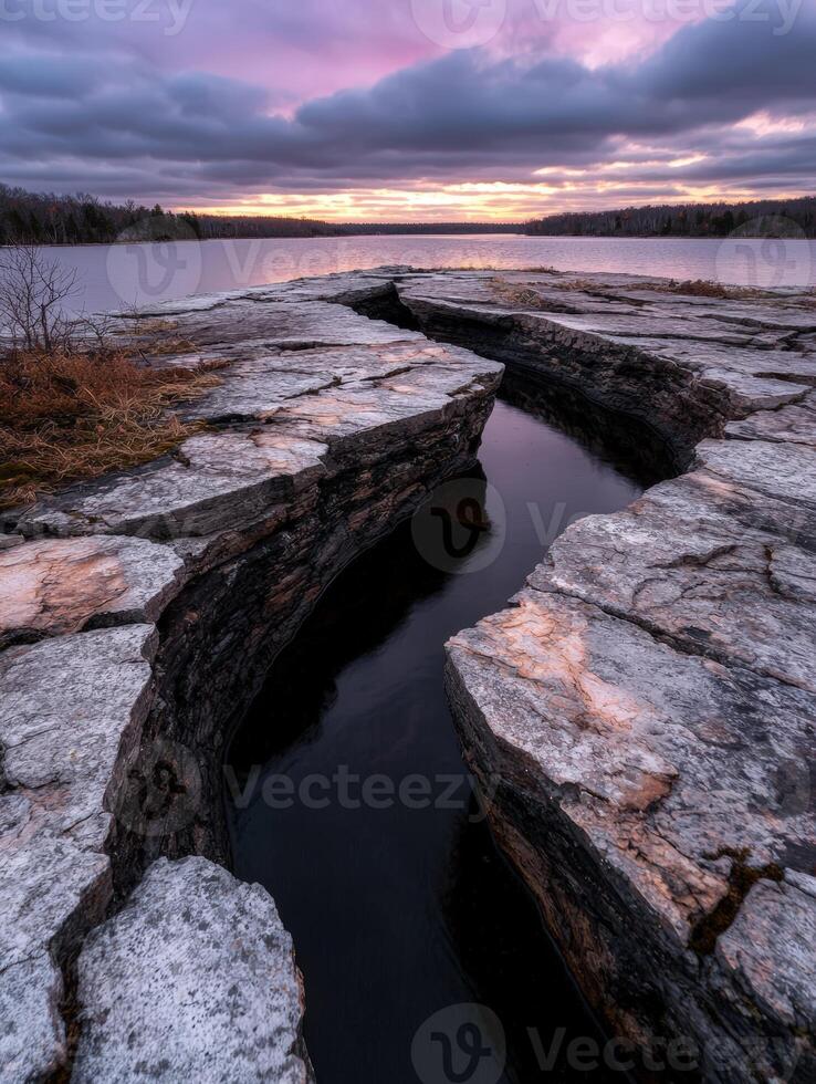 Dramatic rock fissure filled with water at sunset photo