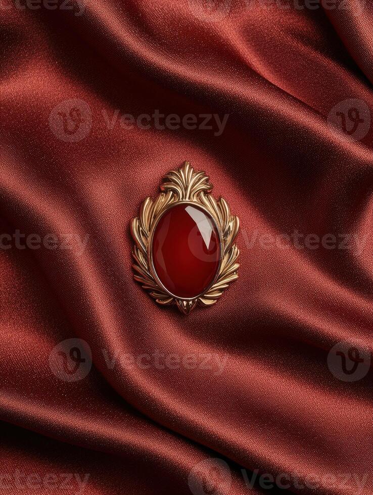 Elegant gold brooch with red gemstone on silk fabric photo