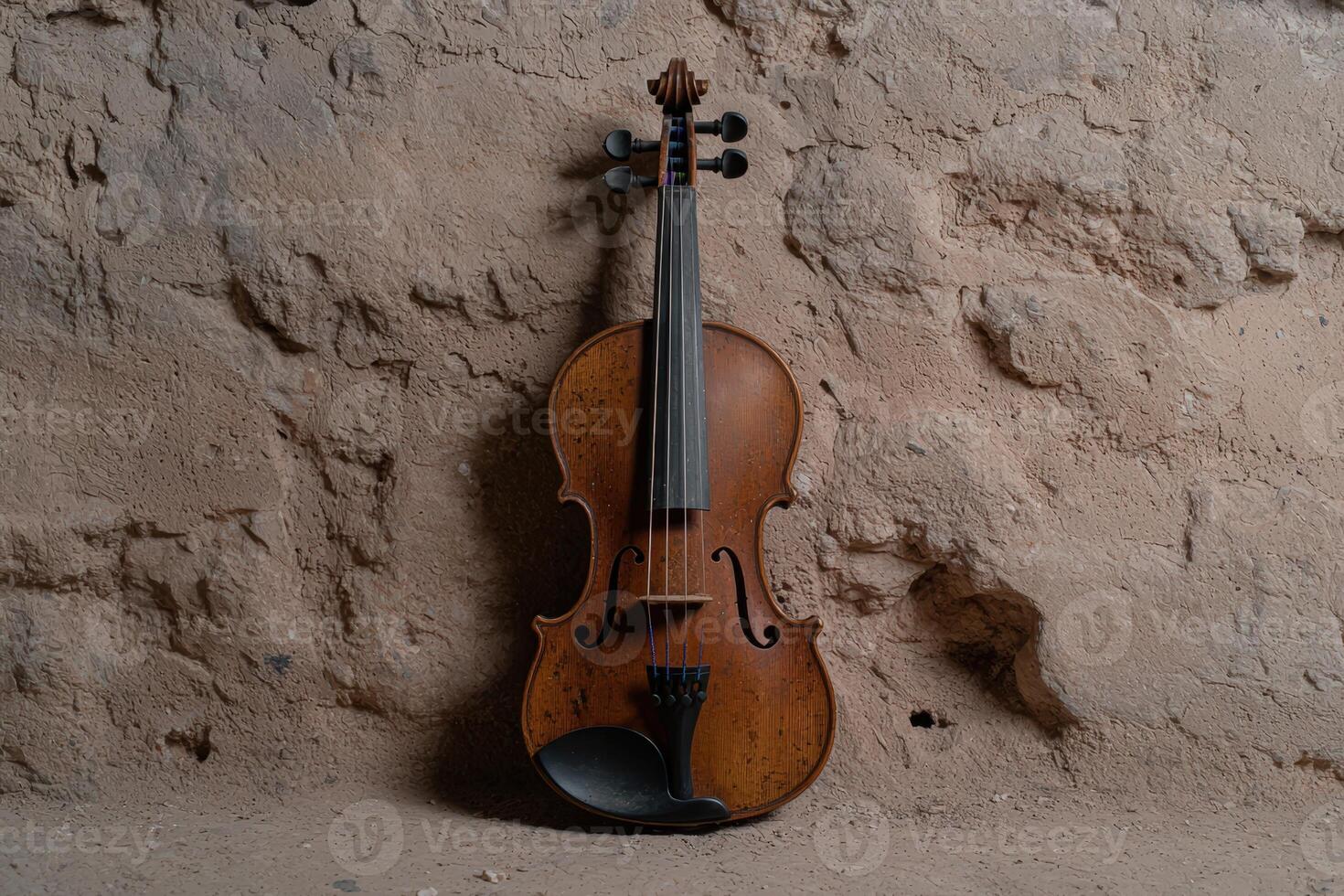 Antique violin rests against a textured, rustic stone wall photo