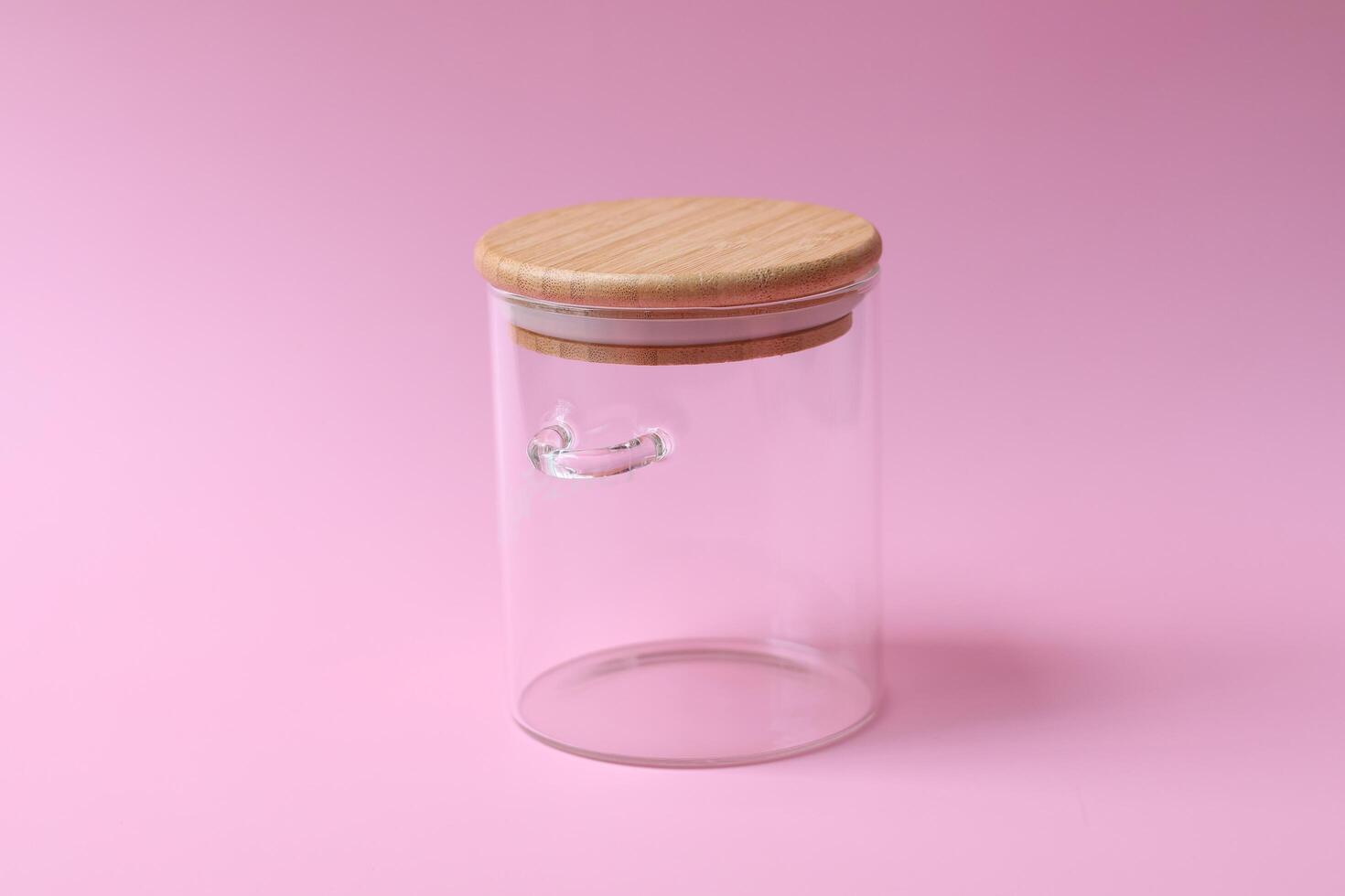 empty glass jar with lid on pink background for food use. Side view photo