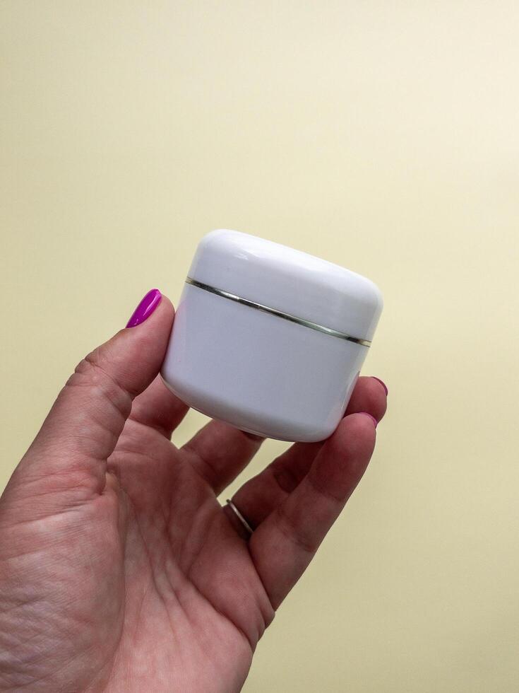Female hand holds cream jar for cosmetics. Packaging for cream, gel, serum, advertising and product promotion, mock up photo