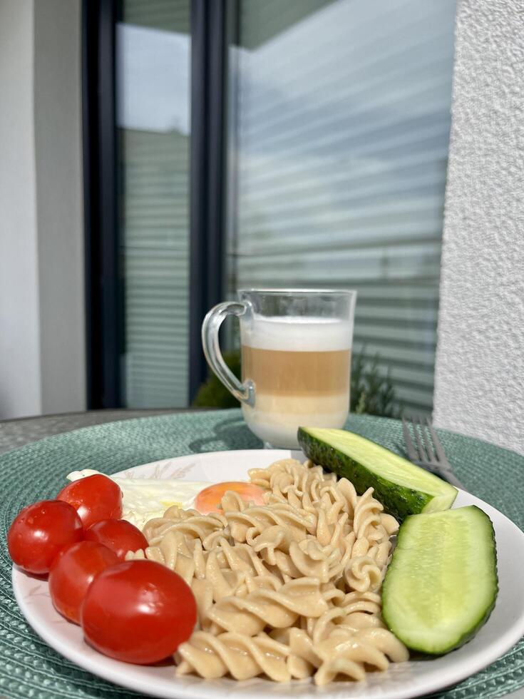 A hearty lunch of pasta, vegetables and scrambled eggs, a glass of coffee, cappuccino in the fresh air on the terrace photo