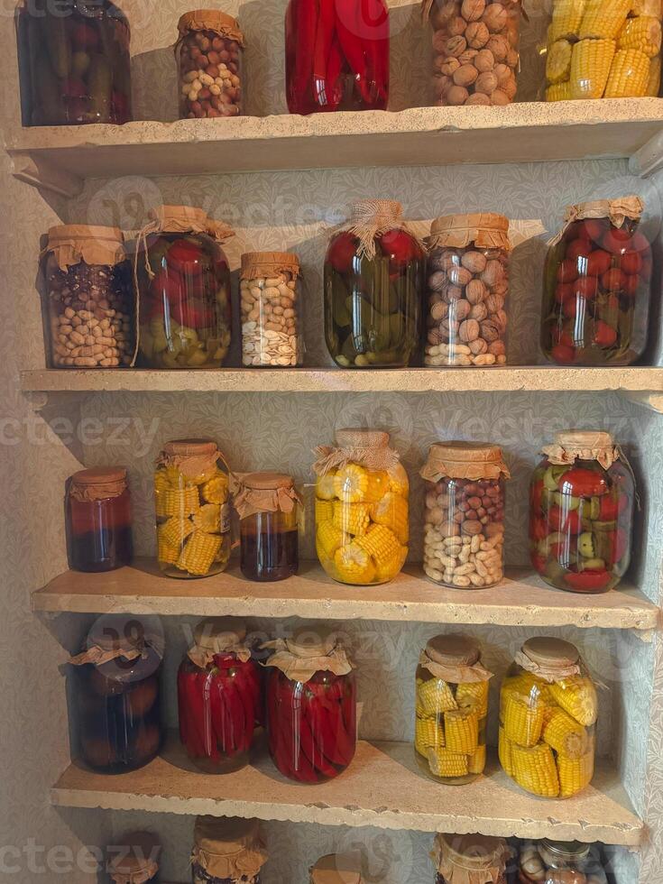 Preserved vegetables and fruits on display in glass jars in a kitchen photo