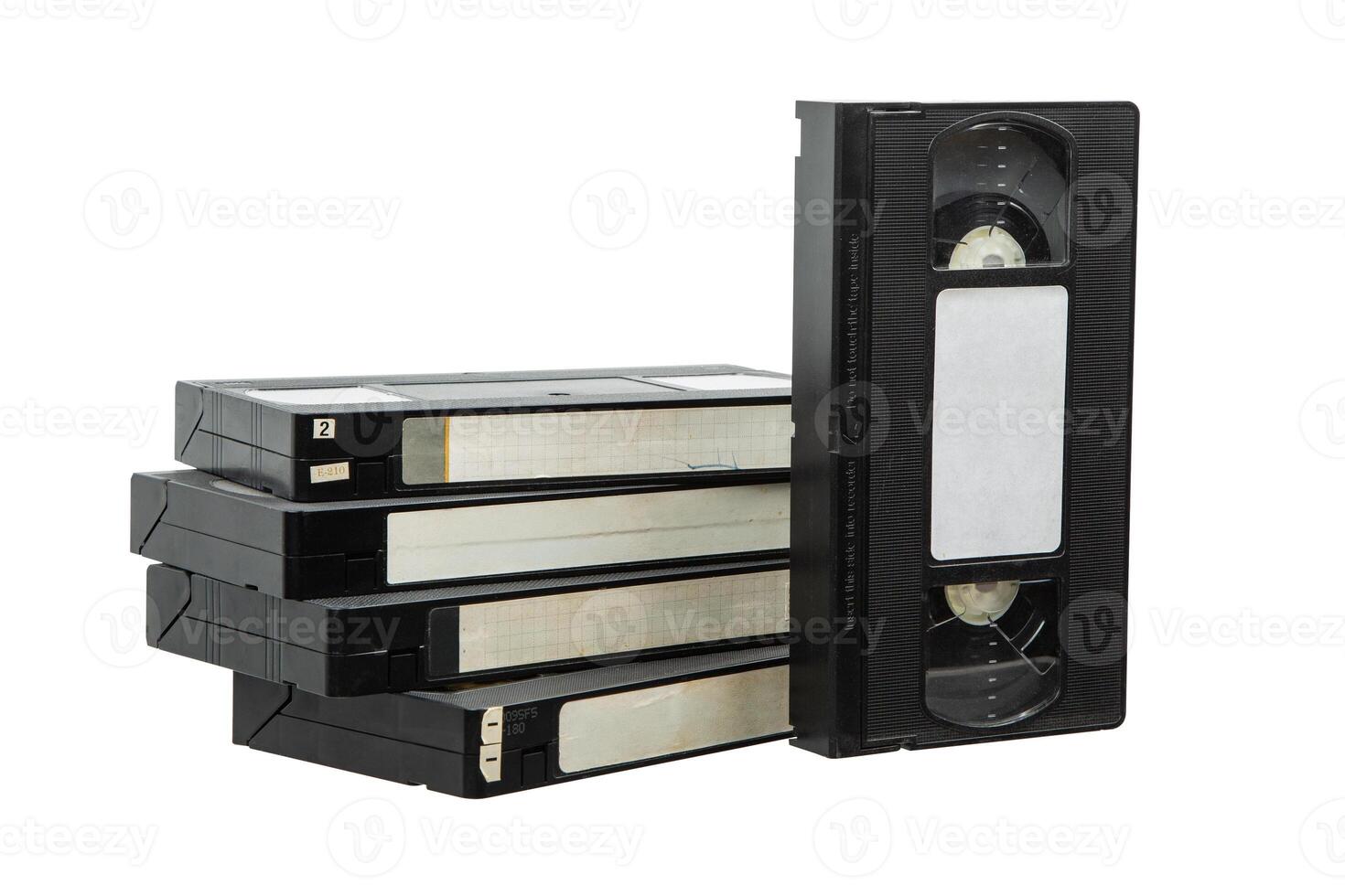 Stack of old VHS tapes with worn labels and one tape standing upright on a white back photo