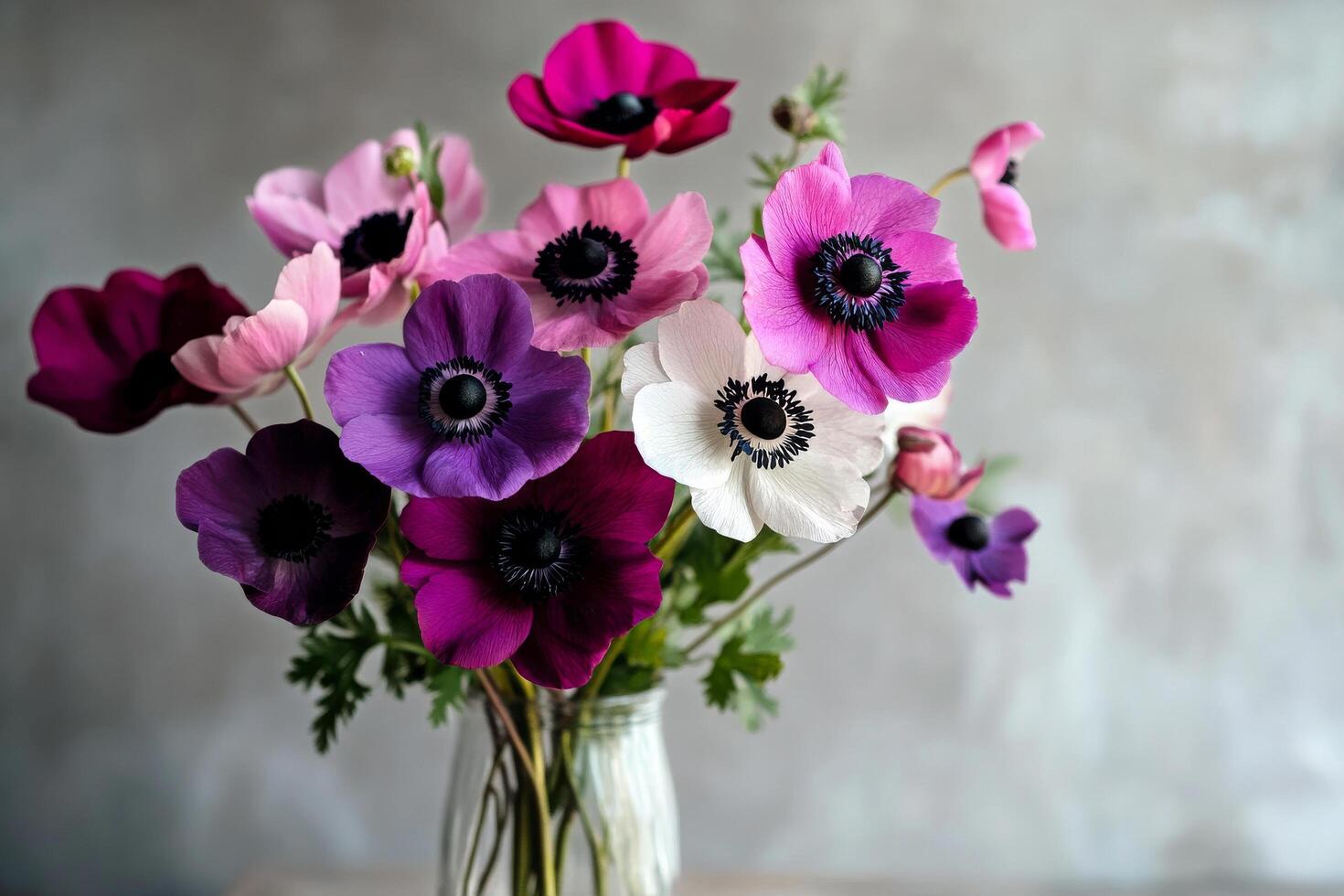 Colorful Anemone Flowers Arranged in a Clear Vase on a Wooden Table. photo