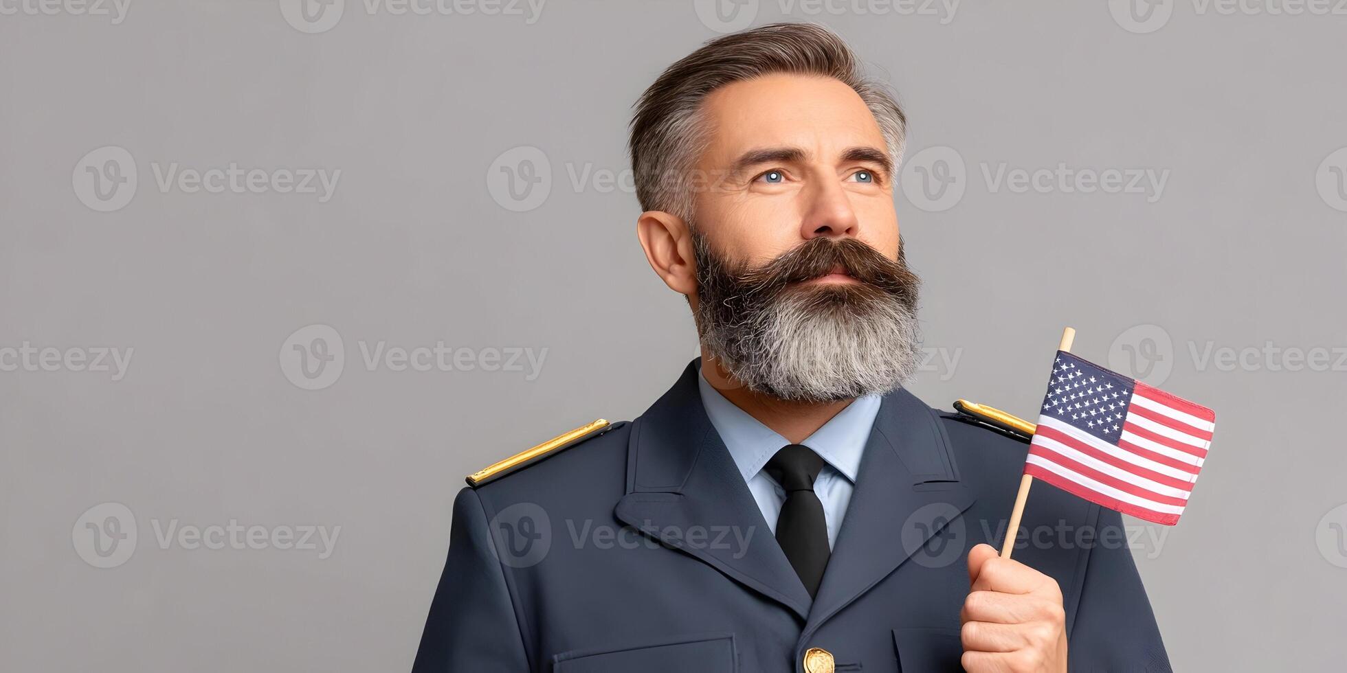 Portrait of a mature man with gray beard in military uniform holding small American flag photo