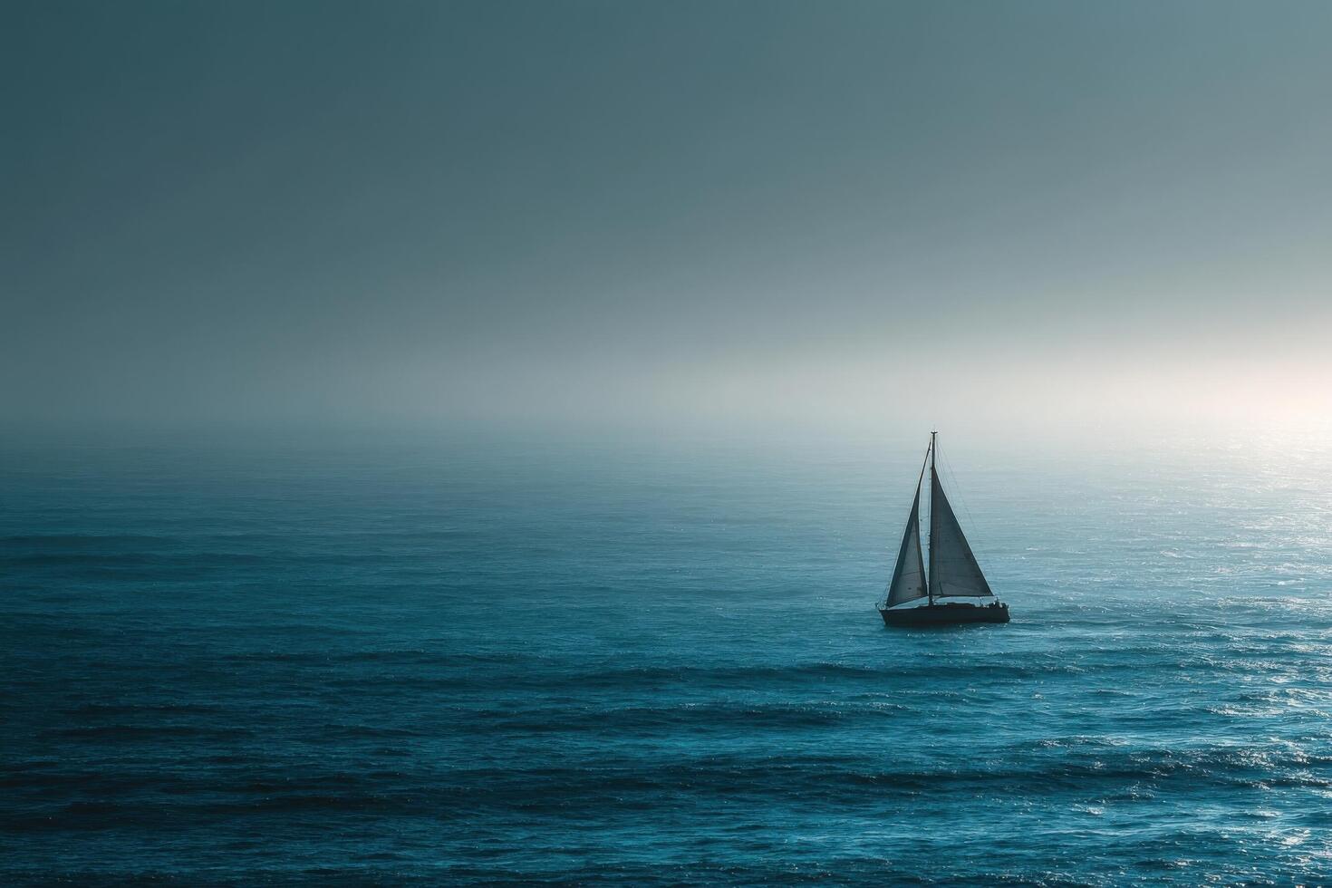A sailboat floating in the ocean on a foggy day photo