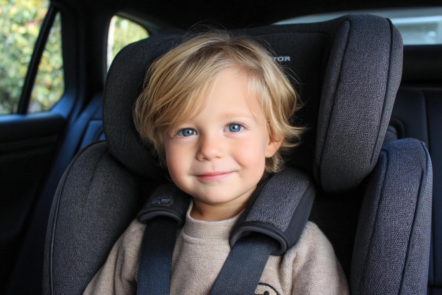 A young boy in a car seat smiling photo