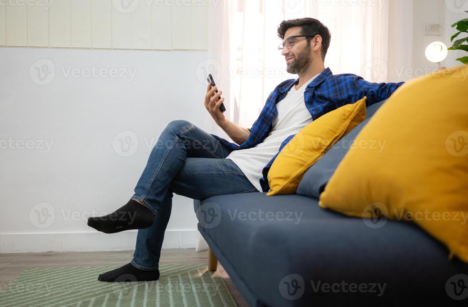 Portrait of a young freelancer using a smartphone and having fun talking in the living room at home,95 photo