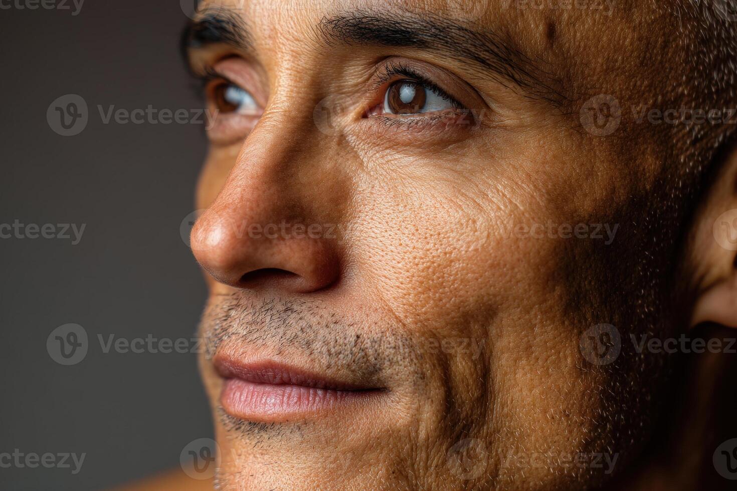 Close-up of a man's face with short hair and visible stubble. Focus on textured skin, deep eyes, and gentle expression. Subtle lighting enhances contours and details vividly photo