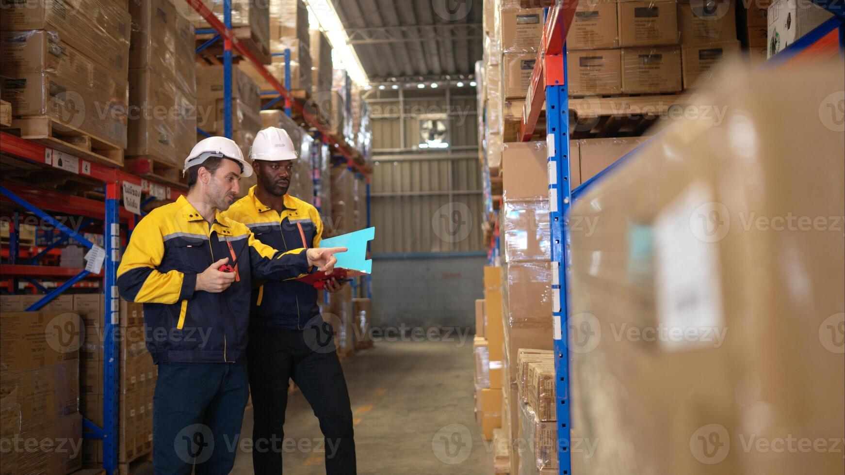Two warehouse workers are reviewing the list of items based on the documentation,85 photo