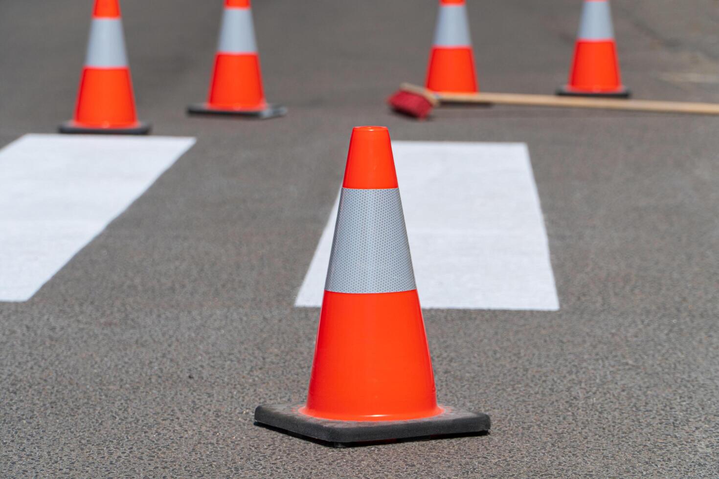 Bright orange traffic cones standing on asphalt. Painting road markings. Traffic cones for road works photo