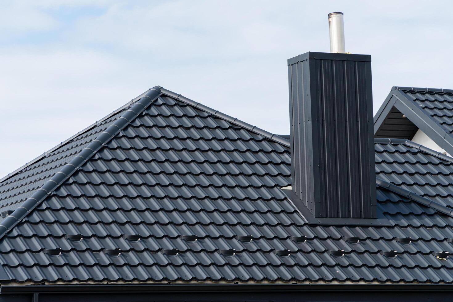 House roof top covered with black metallic shingles. Beautiful modern roof of the house photo