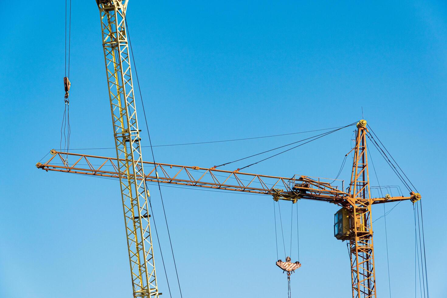 Two yellows hoisting cranes with blue sky background. Machines for construction. Construction concept photo