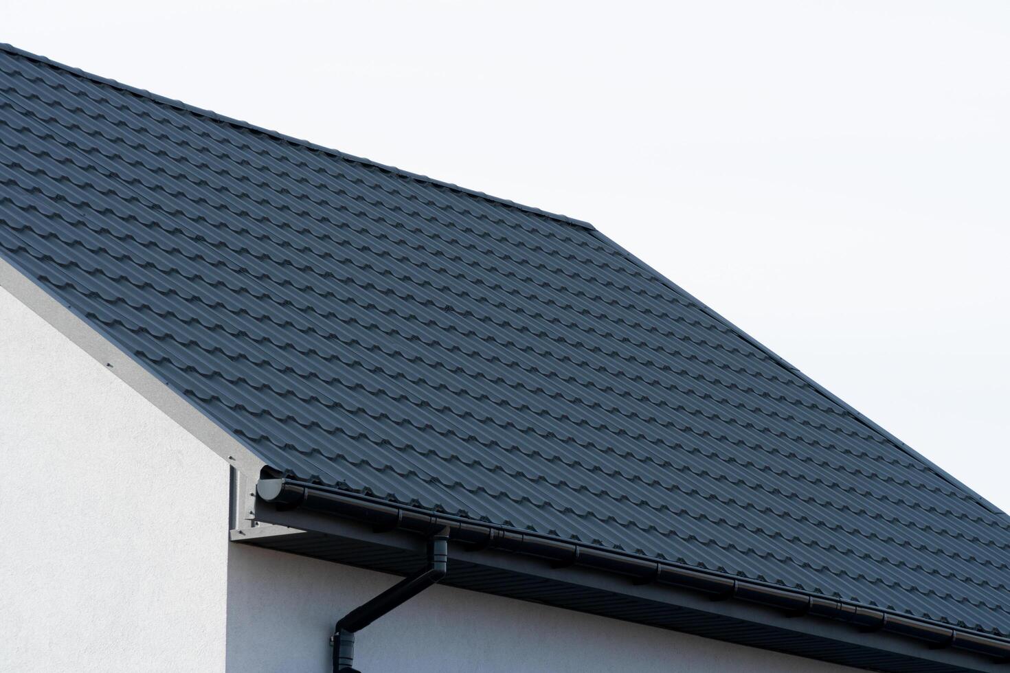 The dark metal roof of a new house. Rain gutter system. Single family house photo
