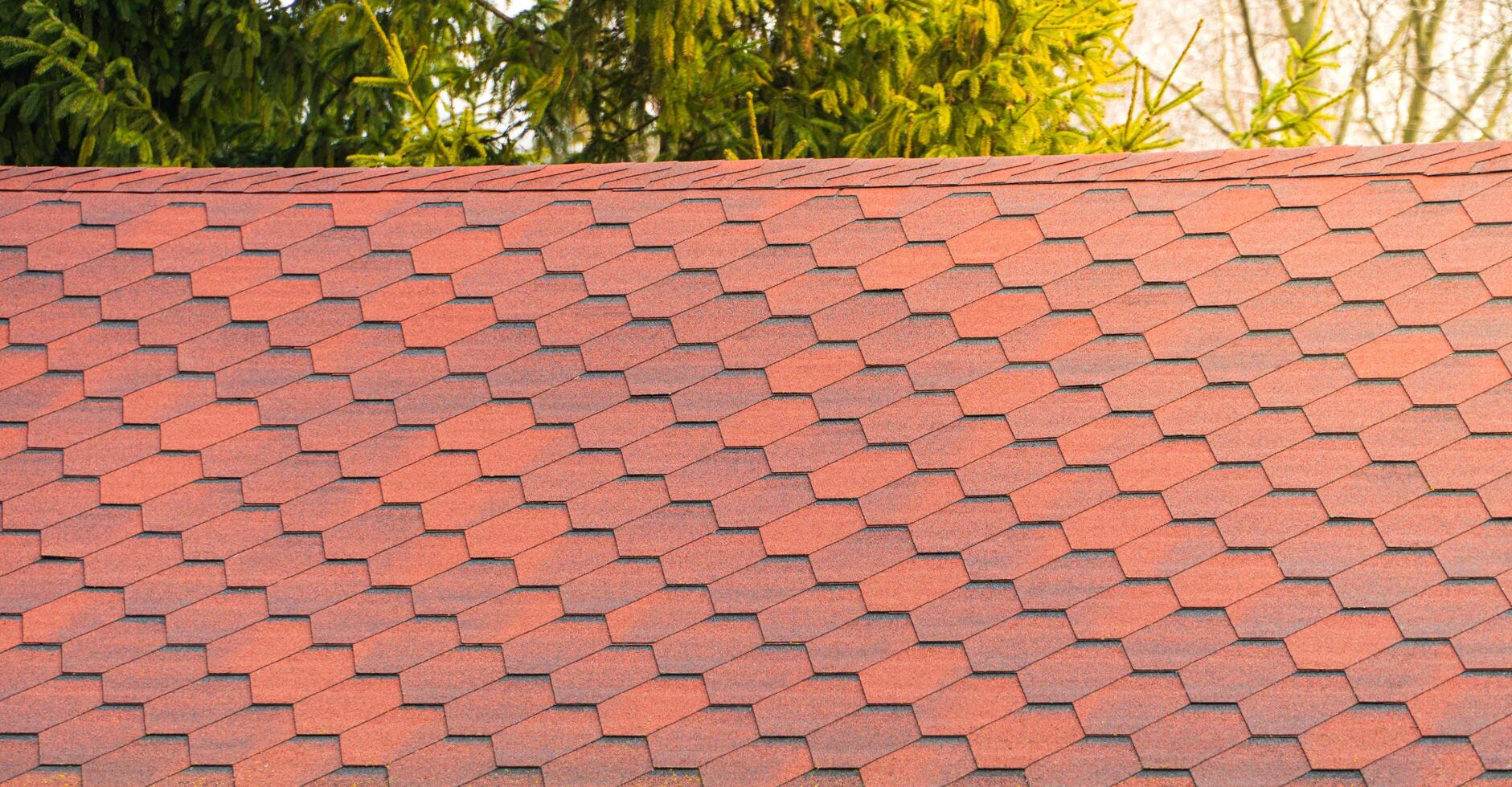 Roof with red bitumen shingles. Modern types of roofing materials photo