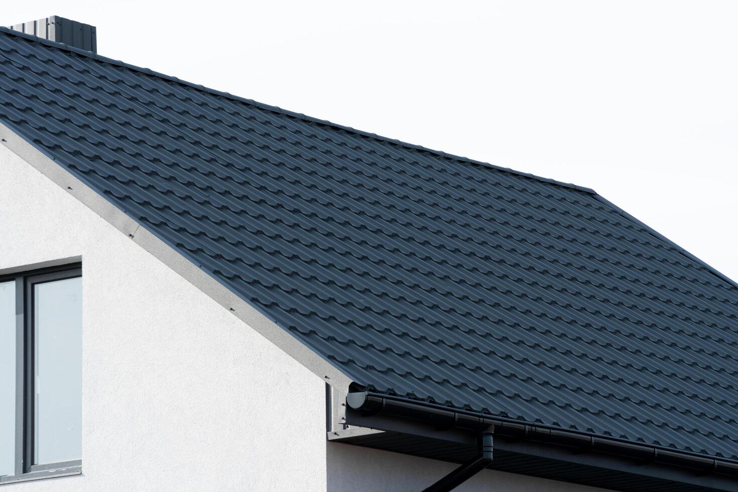 White modern house with black metal roof. Modern metal roof photo