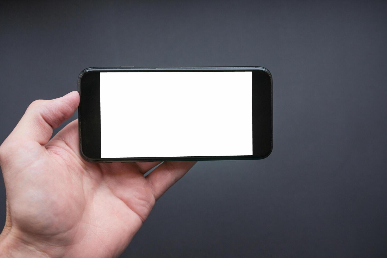 Man holding the black smartphone with blank screen. Smartphone in landscape mode photo