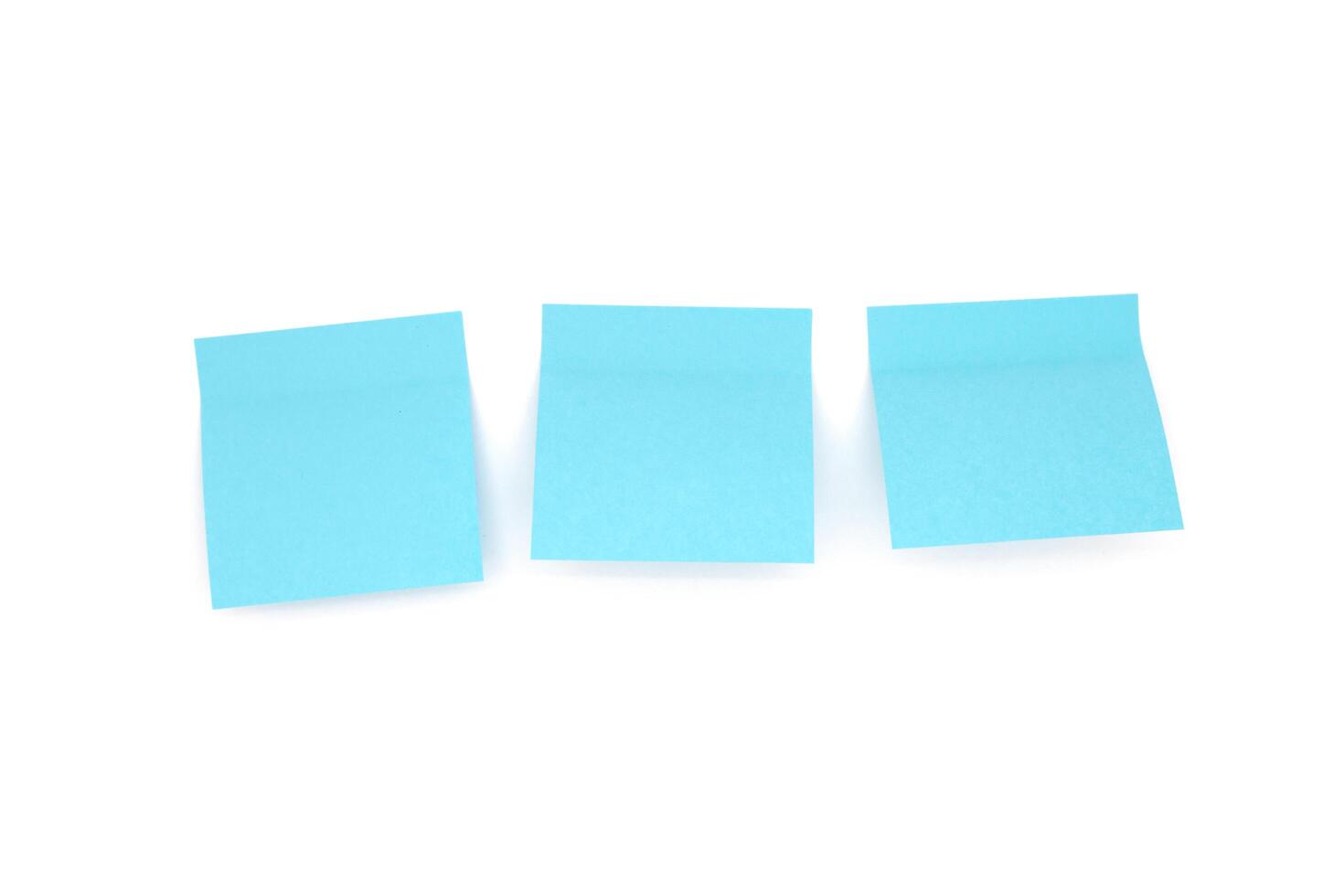 Three blue blank sticky notes on white background. Front view photo