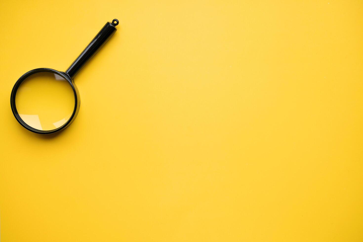Top view of magnifying glass on yellow background, space for text. Search concept photo