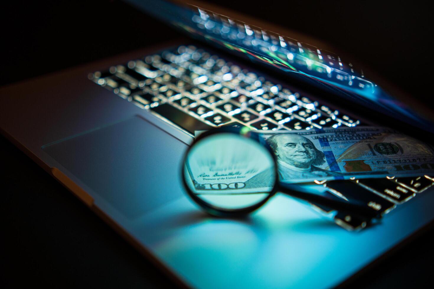A laptop computer with a magnifying glass and a hundred dollars. Business concept. Soft focus photo