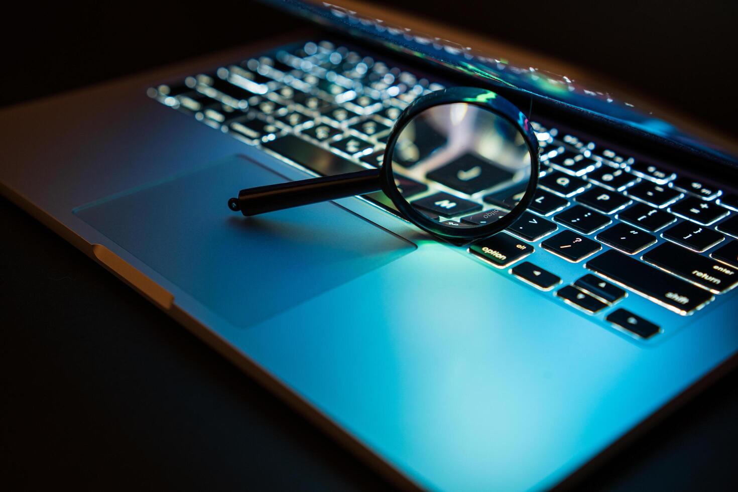 A magnifying glass is placed on a notebook computer. Search for viruses on a laptop computer photo