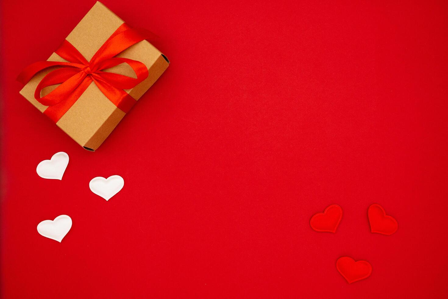 Top view photo of craft paper gift box with ribbon bow on isolated red background with copy space. The concept of the weddings, birthday and other holidays