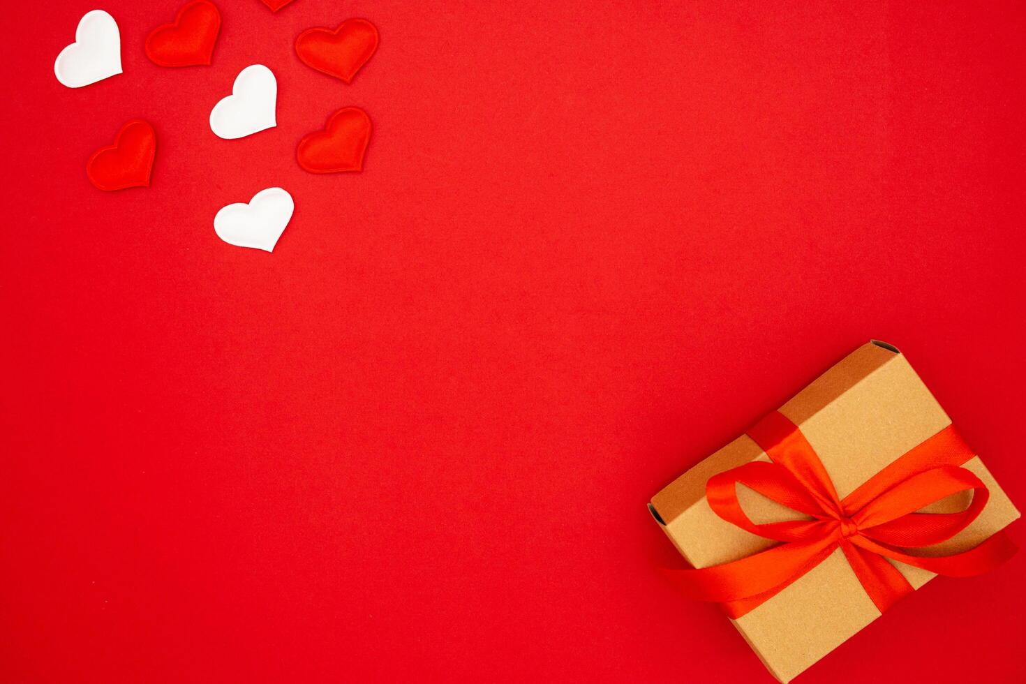 Beautiful gift box and hearts on red background, flat lay with space for text photo