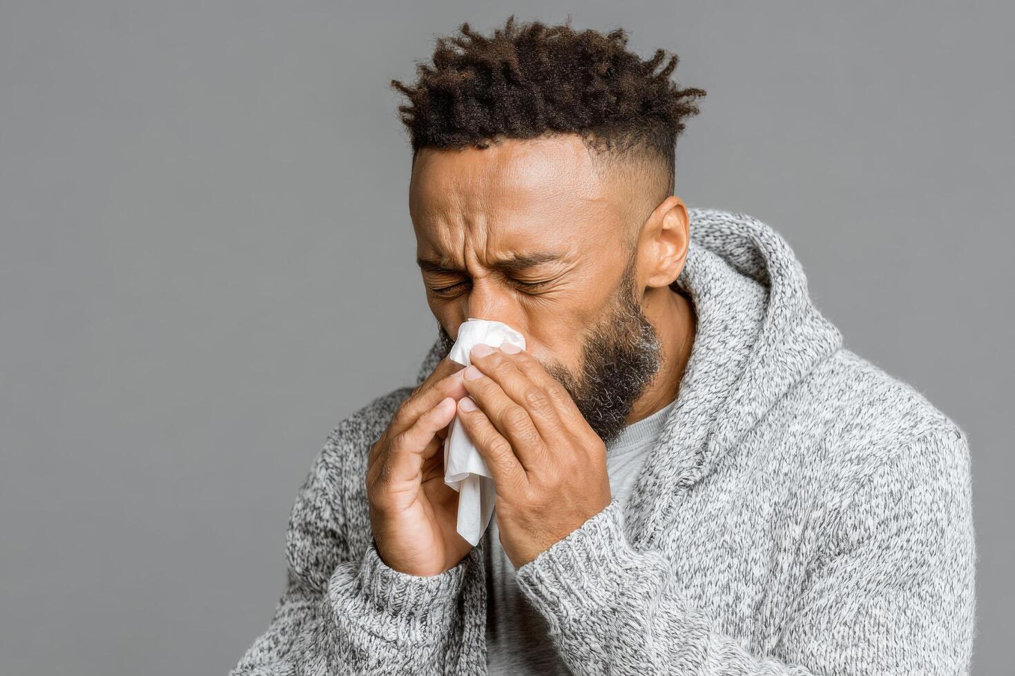 A man blowing his nose with a tissue photo