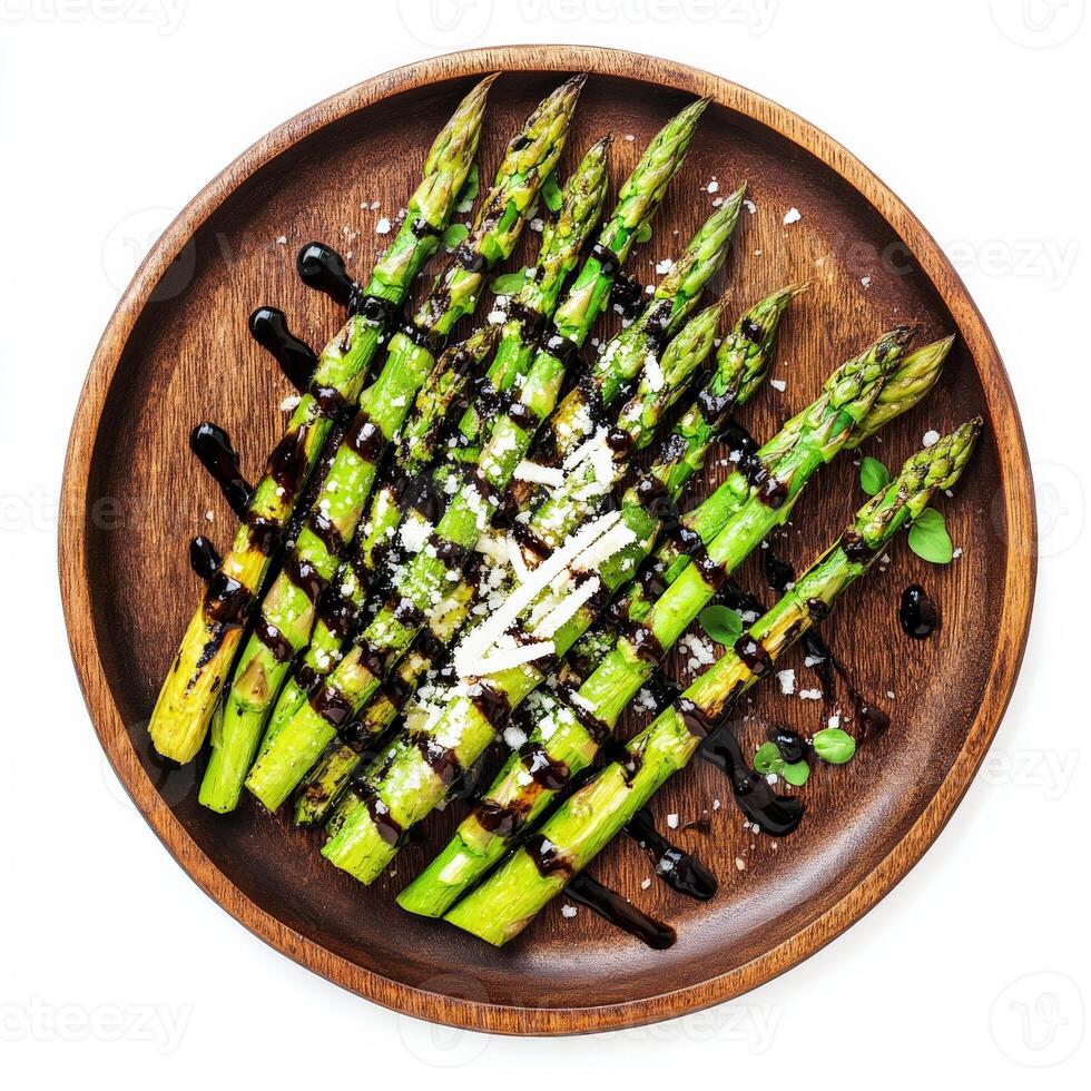 A plate of freshly grilled asparagus, drizzled with balsamic glaze and sprinkled with shaved Parmesan cheese, served on a rustic wooden plate. A simple and flavorful side dish. Isolated on clean white background photo