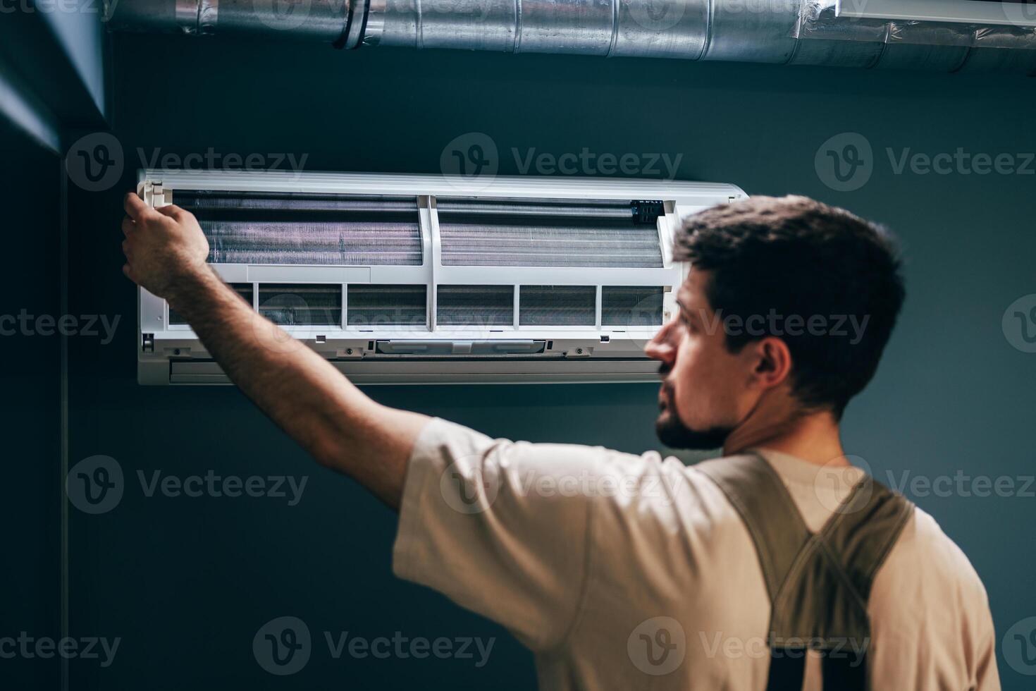 Technician installs air conditioning unit in modern indoor space during warm afternoon photo