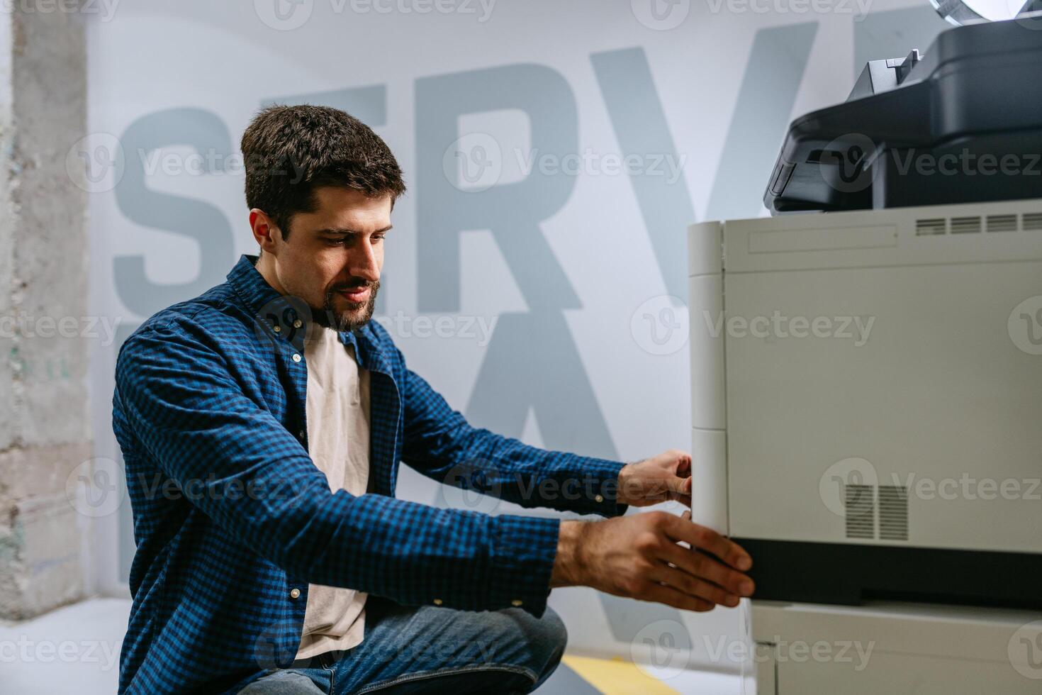 Technologist working with office printer in modern workspace on bright day photo