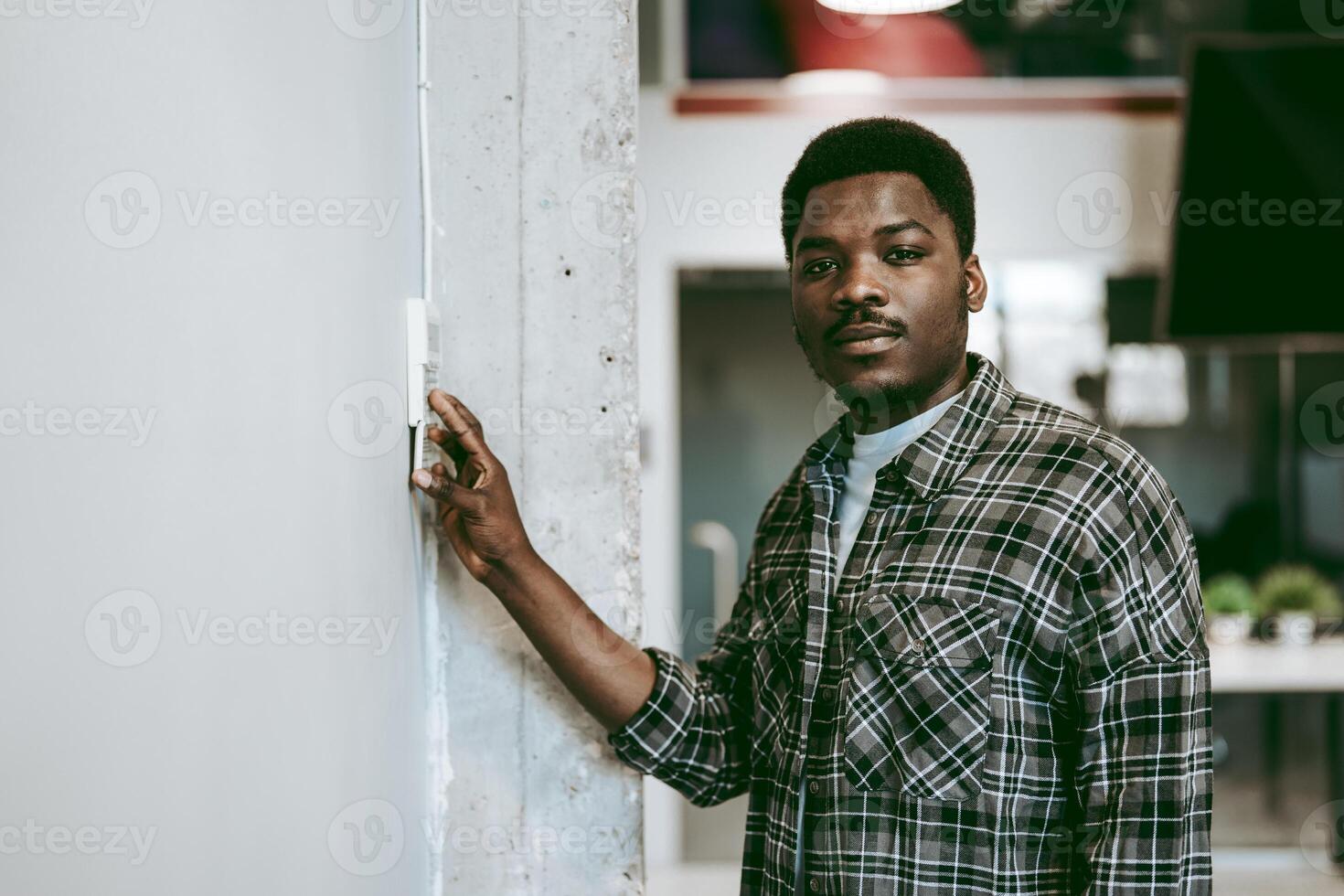 Young man adjusting light switch in modern workspace during bright daytime photo