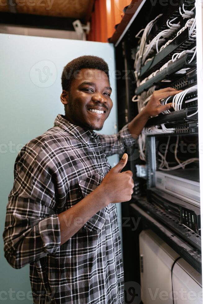 Technician organizes network equipment while smiling in data center during afternoon hours photo