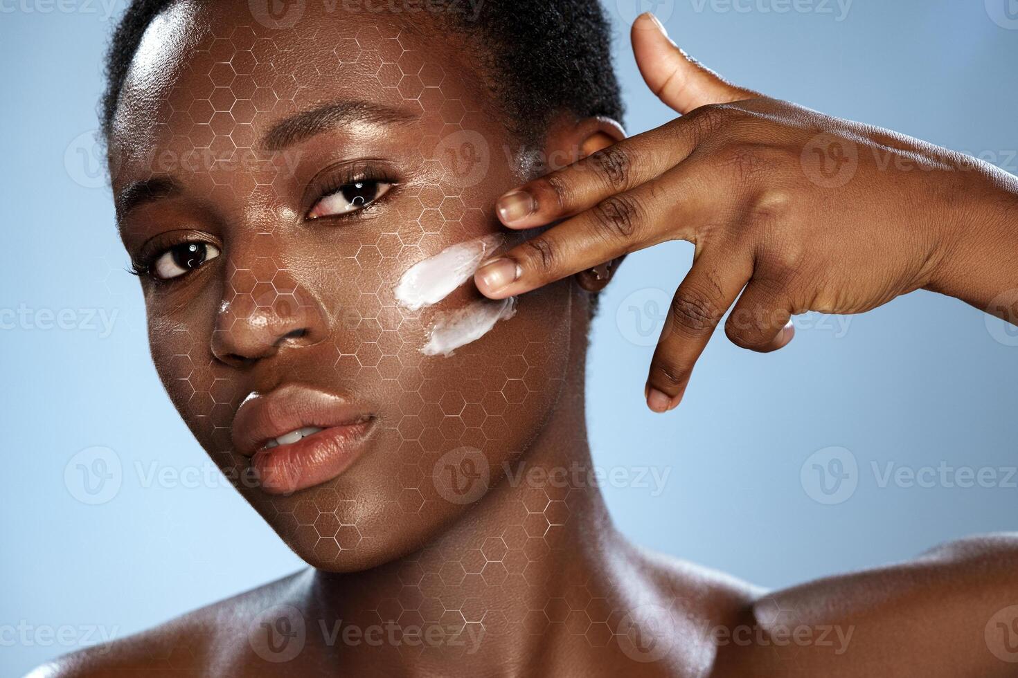 Woman applying skincare product on her face against a blue background showcasing a honeycomb pattern photo