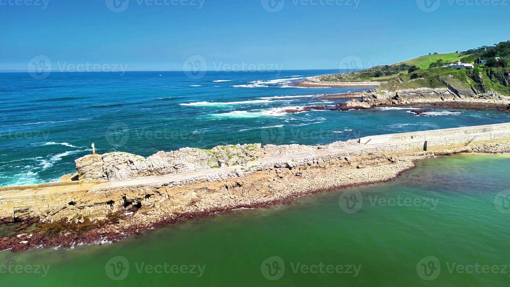 An absolutely breathtaking and stunning aerial view of the sparkling blue ocean and rocky shoreline beneath clear skies photo
