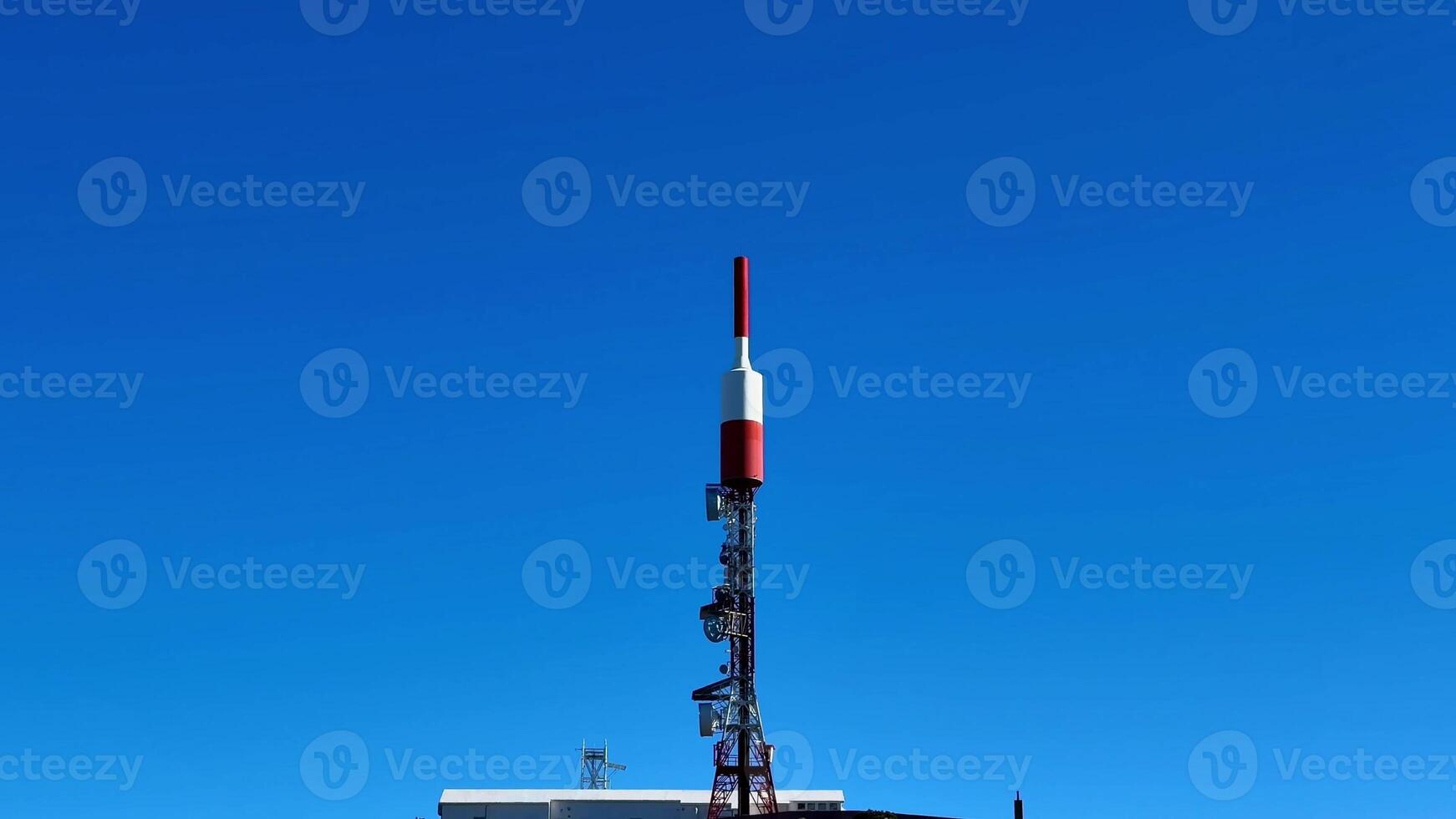 A large antenna tower with a red and white flag photo
