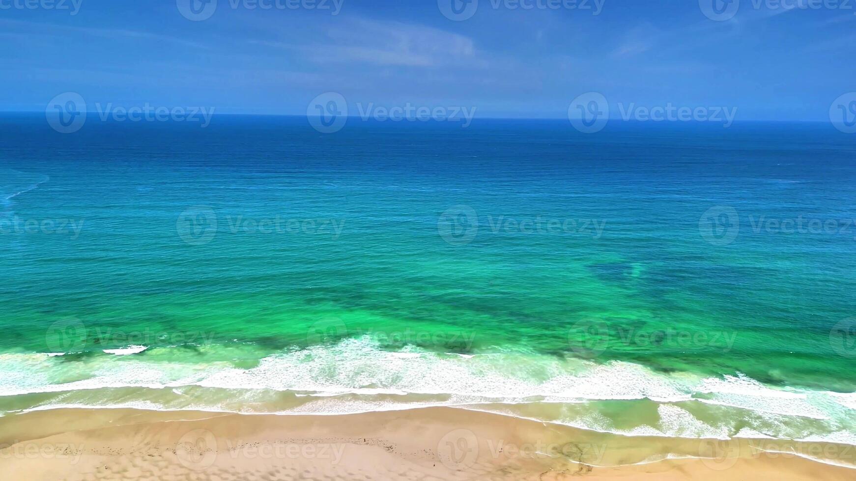 A breathtaking aerial view showcasing the vibrant turquoise ocean waves gently lapping against the sandy shore photo