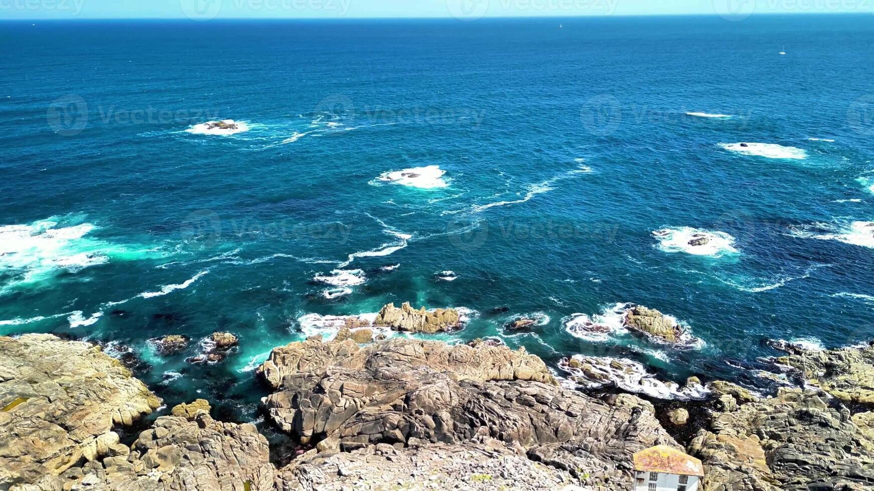 Stunning aerial shots of a rugged coastline with crashing waves and clear blue waters in remarkable detail photo