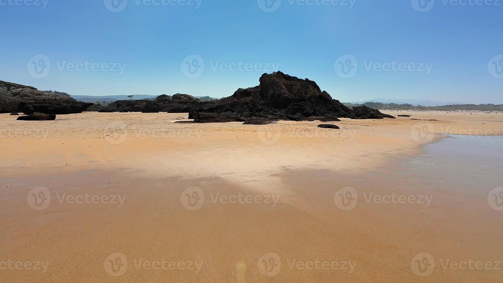 A serene beach with golden sands, rocky outcrops, and a breathtaking blue sky, inviting exploration photo