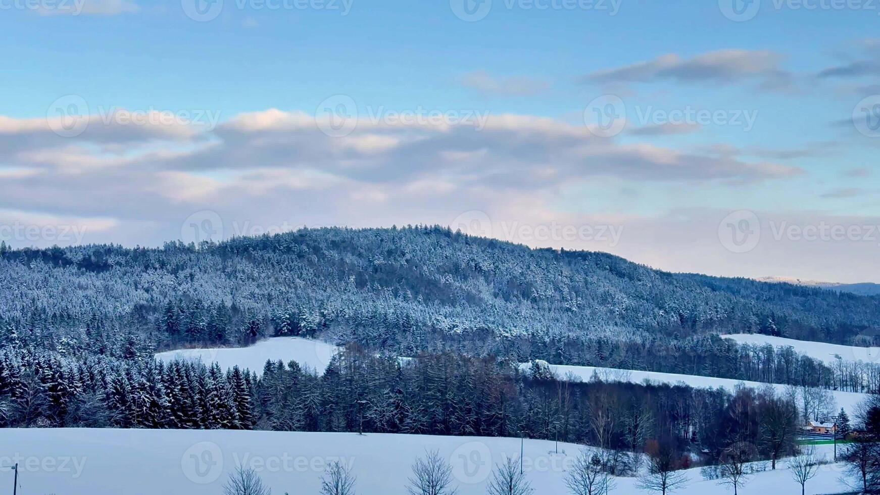 A beautifully peaceful and tranquil winter scene featuring hills blanketed with fresh snow under a clear blue sky photo