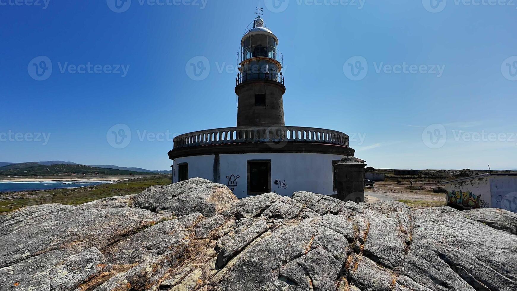 A picturesque scenic view of a charming lighthouse surrounded by rugged rocky terrain and a clear blue sky photo